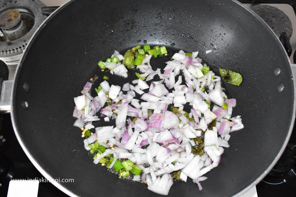 When the green chillies fry lightly, add chopped onions to the kadai / pan.