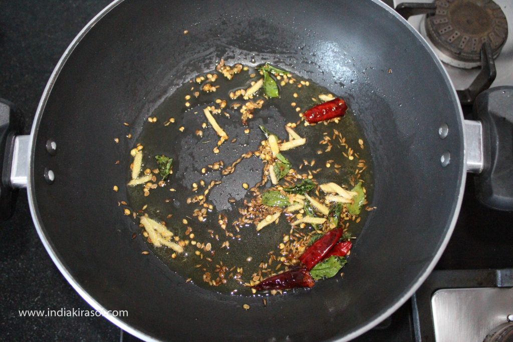 When the ginger is fried, add a pinch of asafoetida, half teaspoon fenugreek seeds, curry leaves, 2 red chillies to the kadhai/ fry pan.