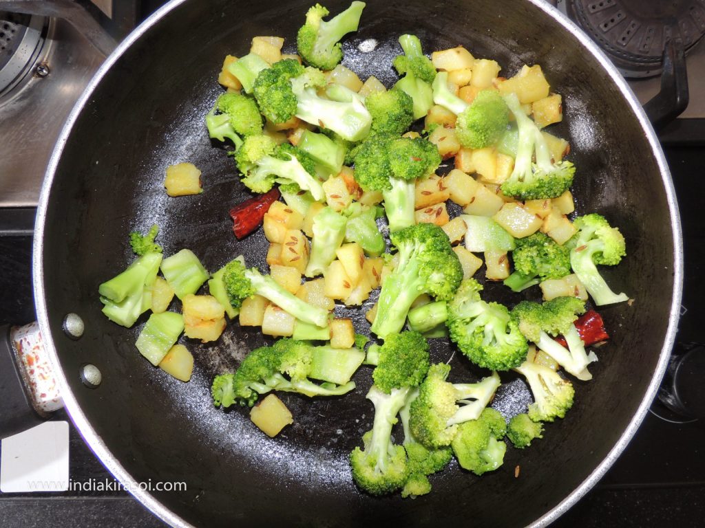 If the potato is cooked, add chopped broccoli in the kadhai/ fry pan.