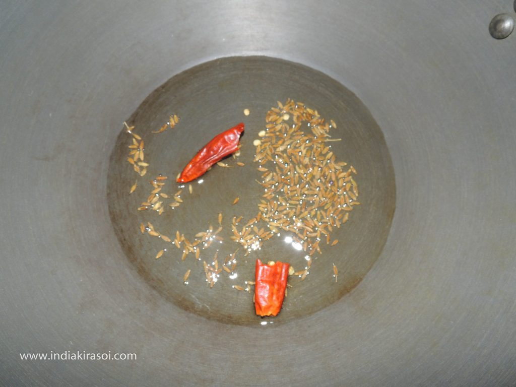When the cumin seeds crackle, add the red chilies to the oil.
