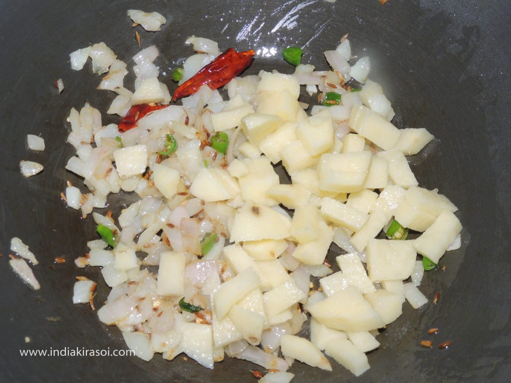 When the onion is fried, add chopped potatoes in the kadhai/fry.