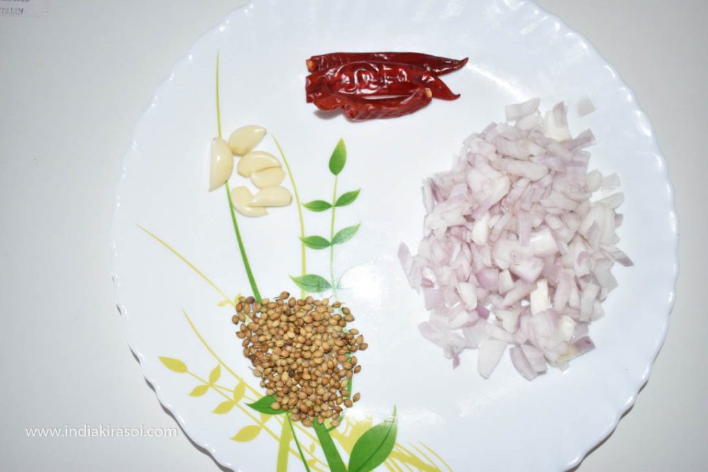 Cut one onion, take 4 garlic cloves with it and take 2 whole red chilies. Take 1 spoon of coriander seeds with it.
