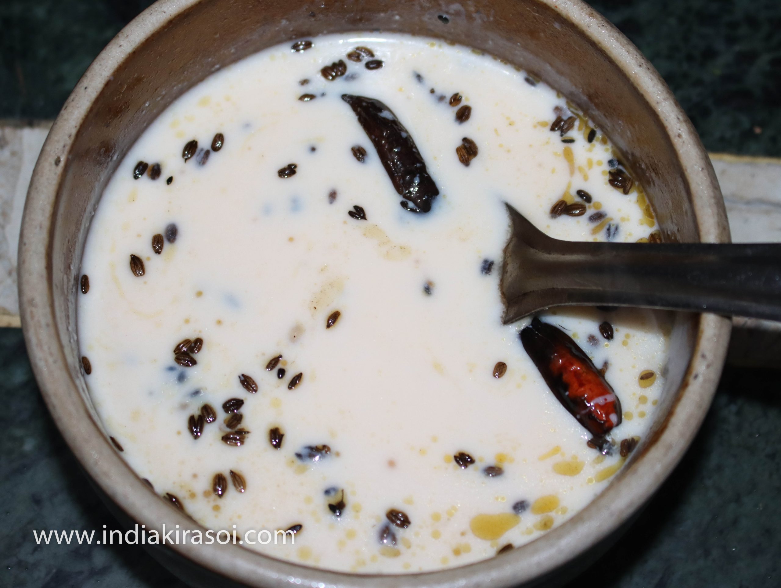After this, pour the tempering in the whey/ mattha, cover the vessel with a plate as soon as you add the tempering. So that the fragrance of asafetida should remain in the whey liquid or mattha.