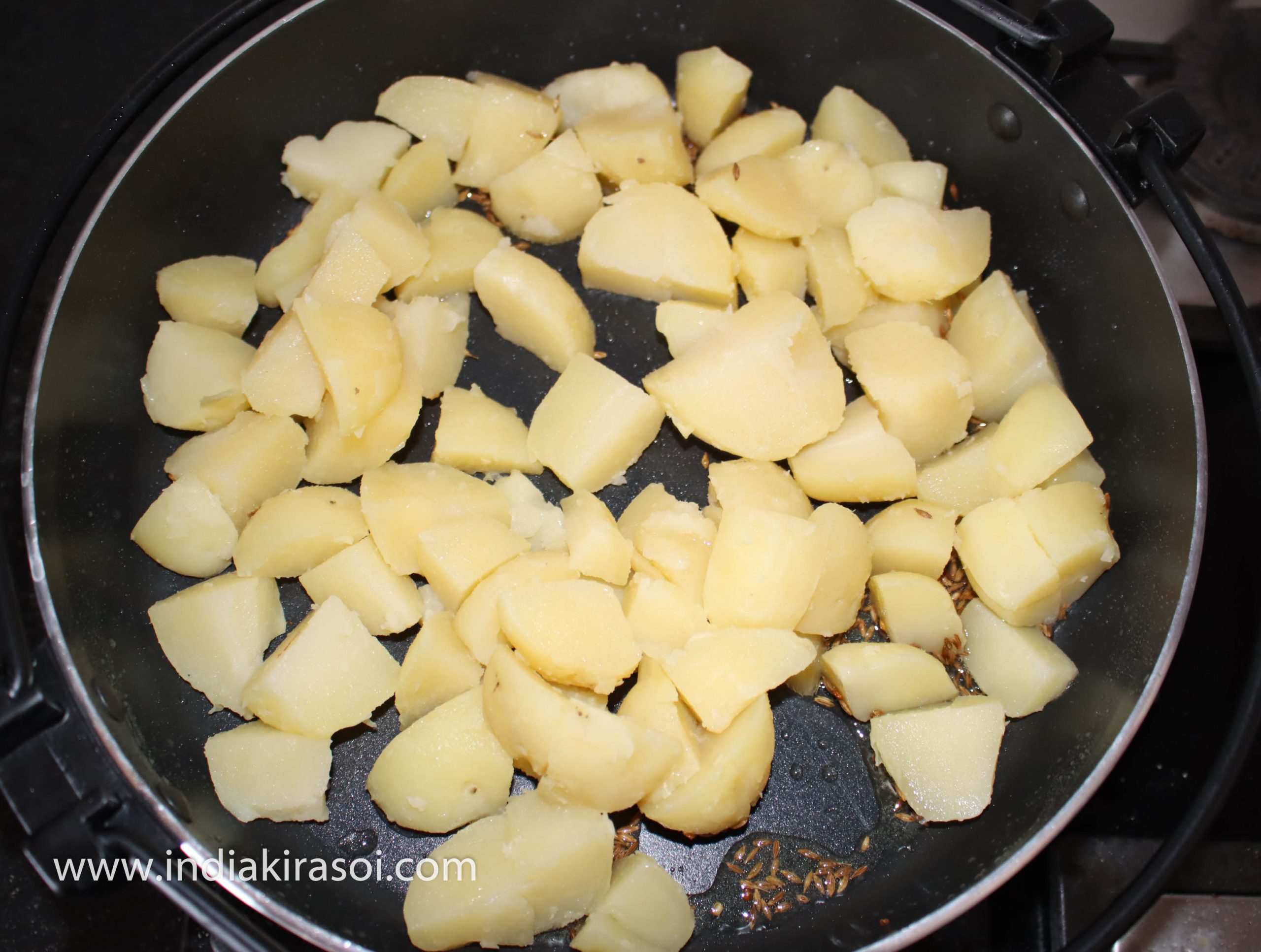 When cumin starts crackle, add chopped potato in it.