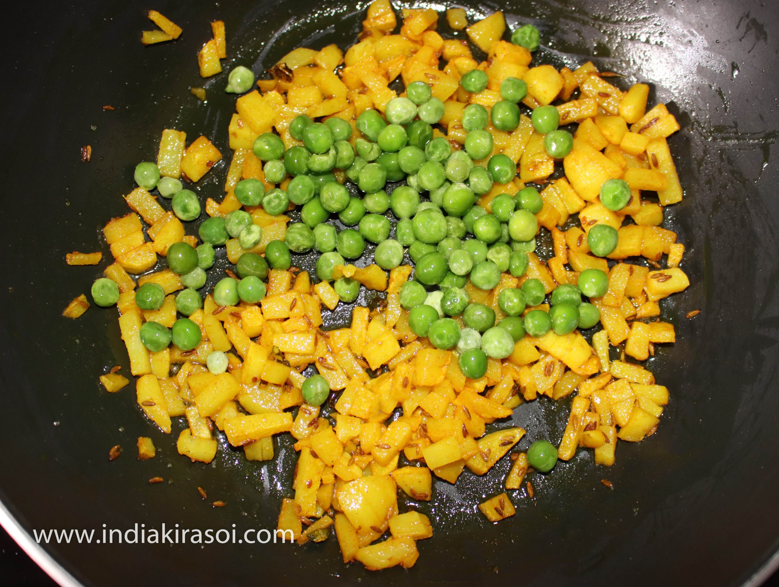 Once the potatoes are cooked add boiled green peas to the potatoes.