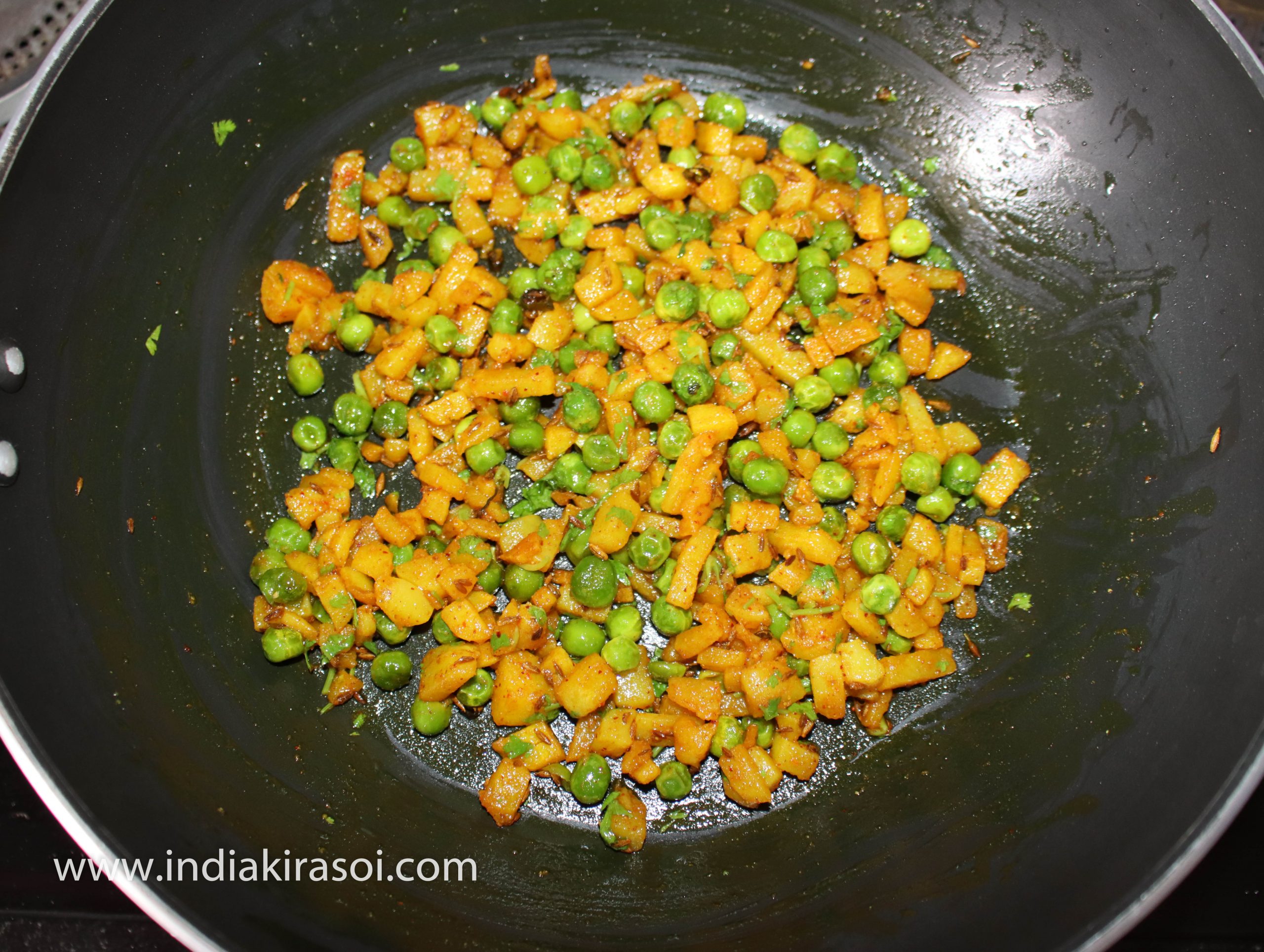 Mix coriander leaves with the curry. Aloo matar sukhi sabji is ready. Switch off the gas.